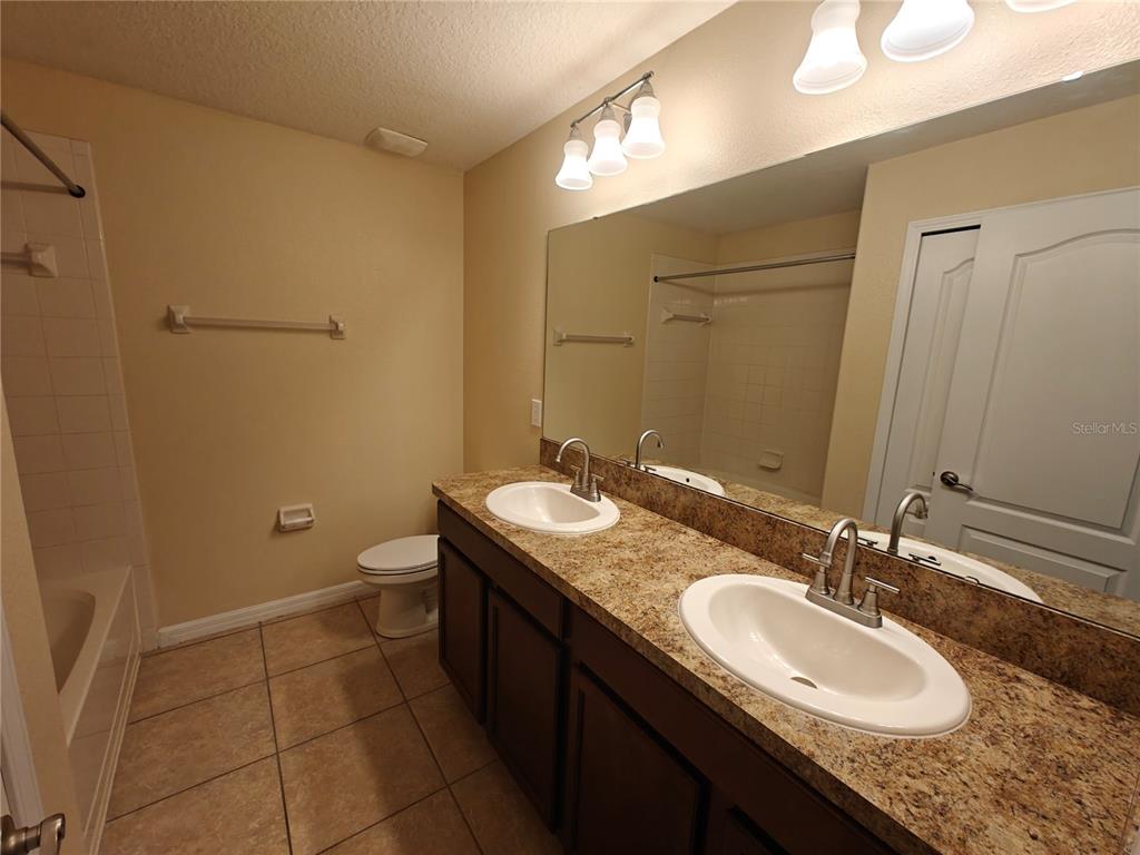 3410 Rodrick Circle Orlando, FL 32824 - Photo 18 of 27 a bathroom with a granite countertop sink a mirror and a toilet