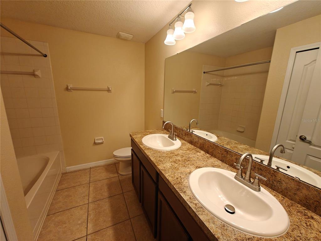 3410 Rodrick Circle Orlando, FL 32824 - Photo 22 of 27 a bathroom with a granite countertop sink toilet and a mirror