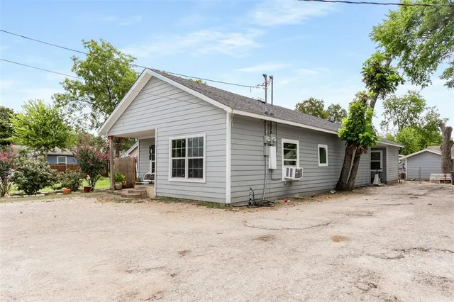 a view of a house with a yard and large tree