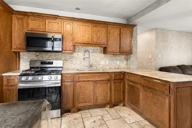 a kitchen with stainless steel appliances granite countertop a stove a sink and a microwave