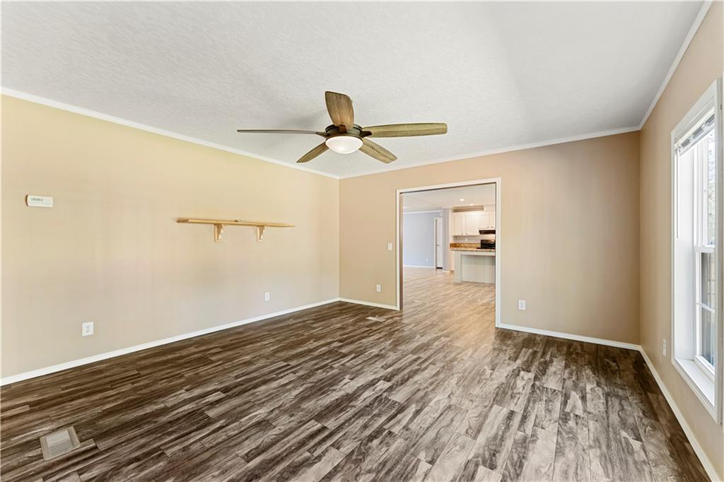 89 Ridge Road Seale, AL 36875 - Photo 18 of 46 Wood-finish flooring throughout, neutral wall tones, ceiling fan with integrated lighting, white trim and crown molding, and window with white frame