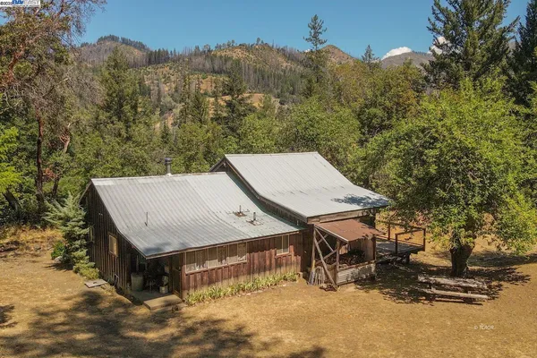 an aerial view of a house with roof deck and covered with tall trees