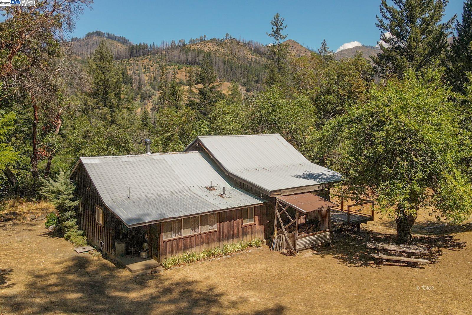 an aerial view of a house with roof deck and covered with tall trees