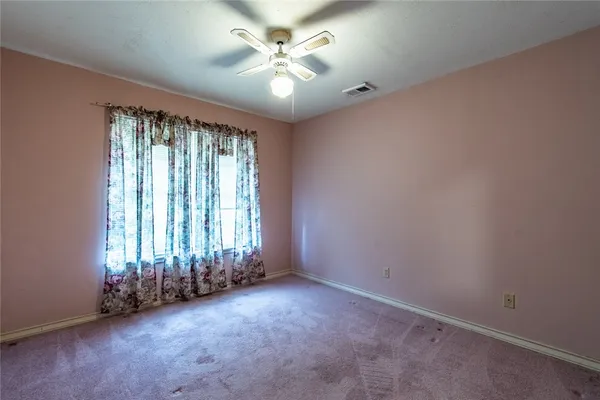 an empty room with windows and a ceiling fan