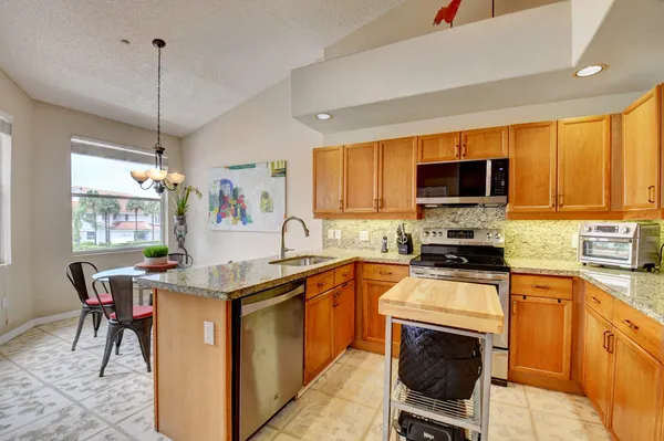a kitchen with stainless steel appliances granite countertop a stove top oven a sink dishwasher a dining table and chairs with wooden floor