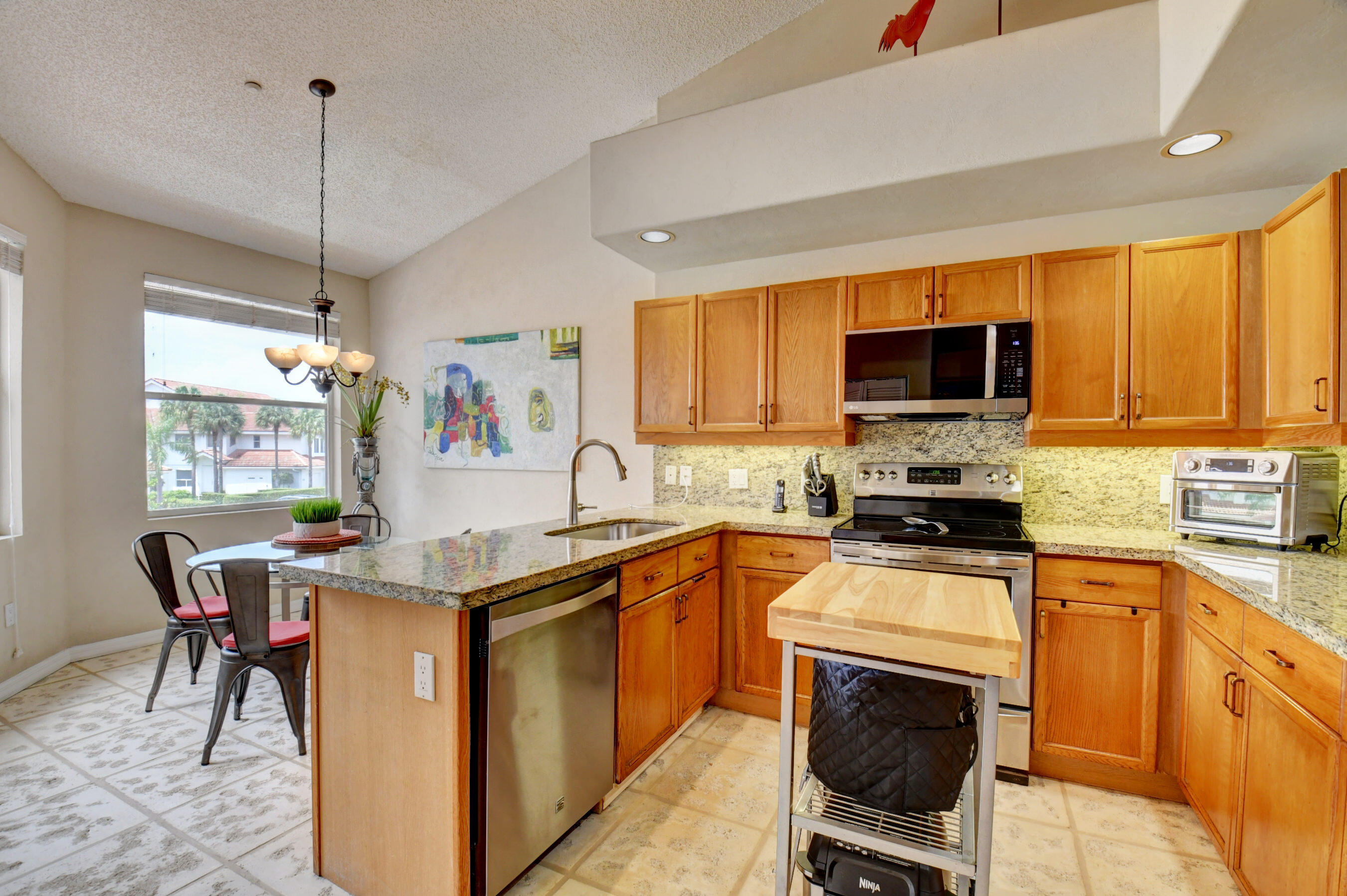 2464 Northwest 59th Street, Unit 1103 Boca Raton, FL 33496 - Photo 6 of 48 a kitchen with stainless steel appliances granite countertop a stove top oven a sink dishwasher a dining table and chairs with wooden floor