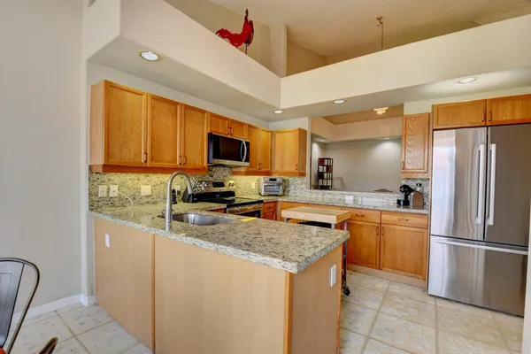 a kitchen with stainless steel appliances granite countertop a refrigerator a stove a sink a microwave oven with a dining table and chairs