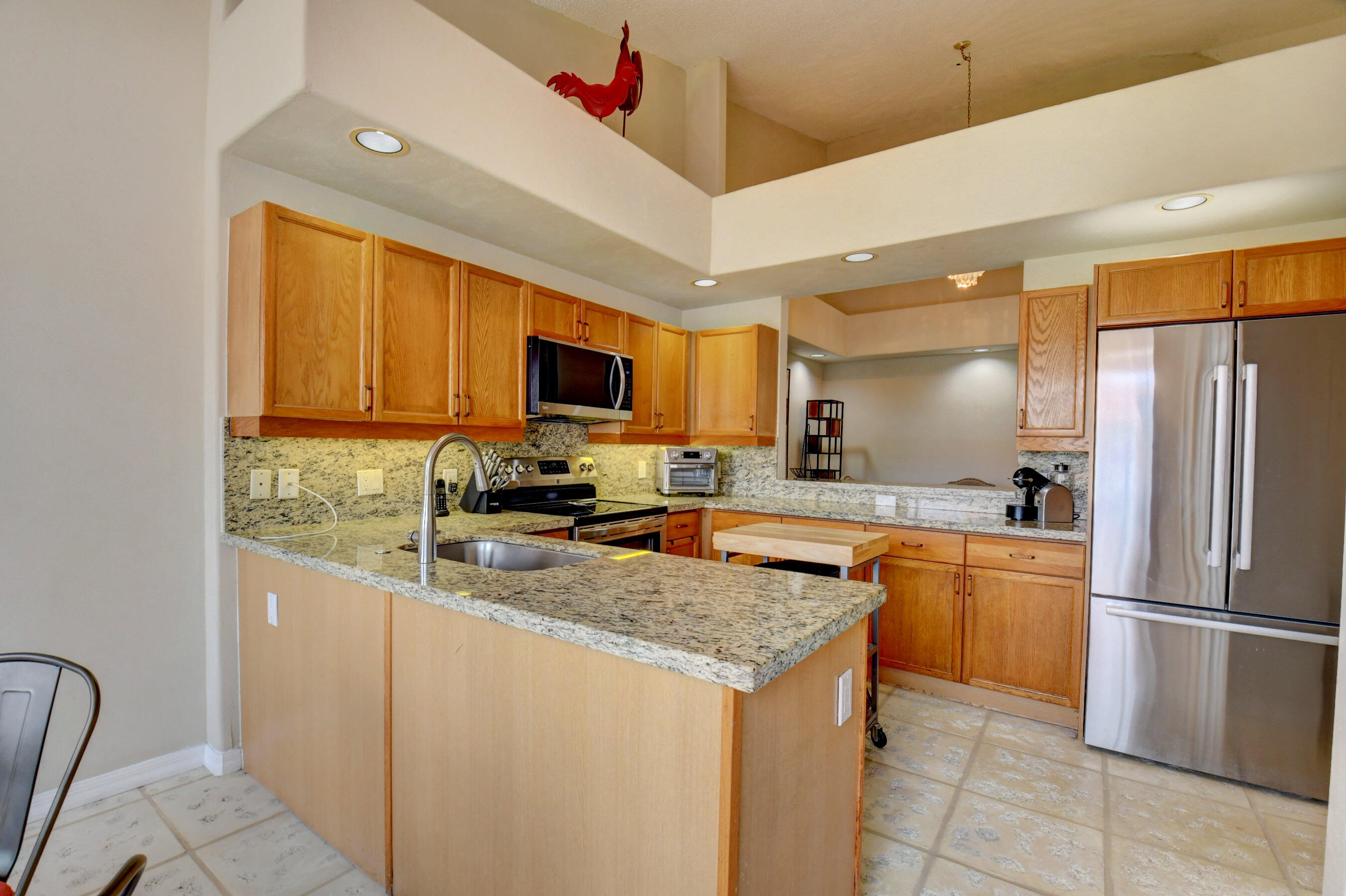 2464 Northwest 59th Street, Unit 1103 Boca Raton, FL 33496 - Photo 8 of 48 a kitchen with stainless steel appliances granite countertop a refrigerator a stove a sink a microwave oven with a dining table and chairs