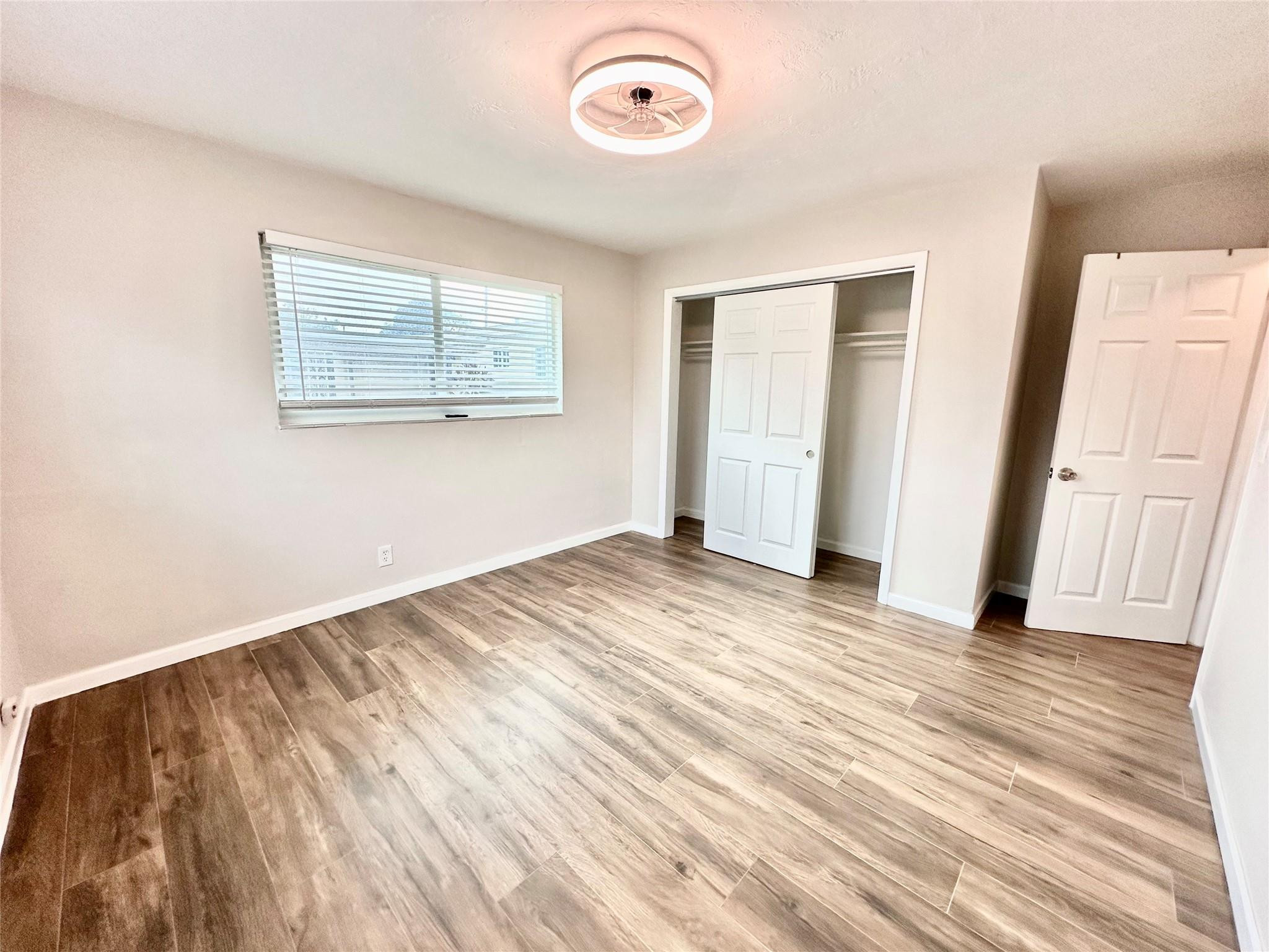 512 Southwest 11th Street, Unit A Hallandale Beach, FL 33009 - Photo 12 of 15 an empty room with wooden floor and windows