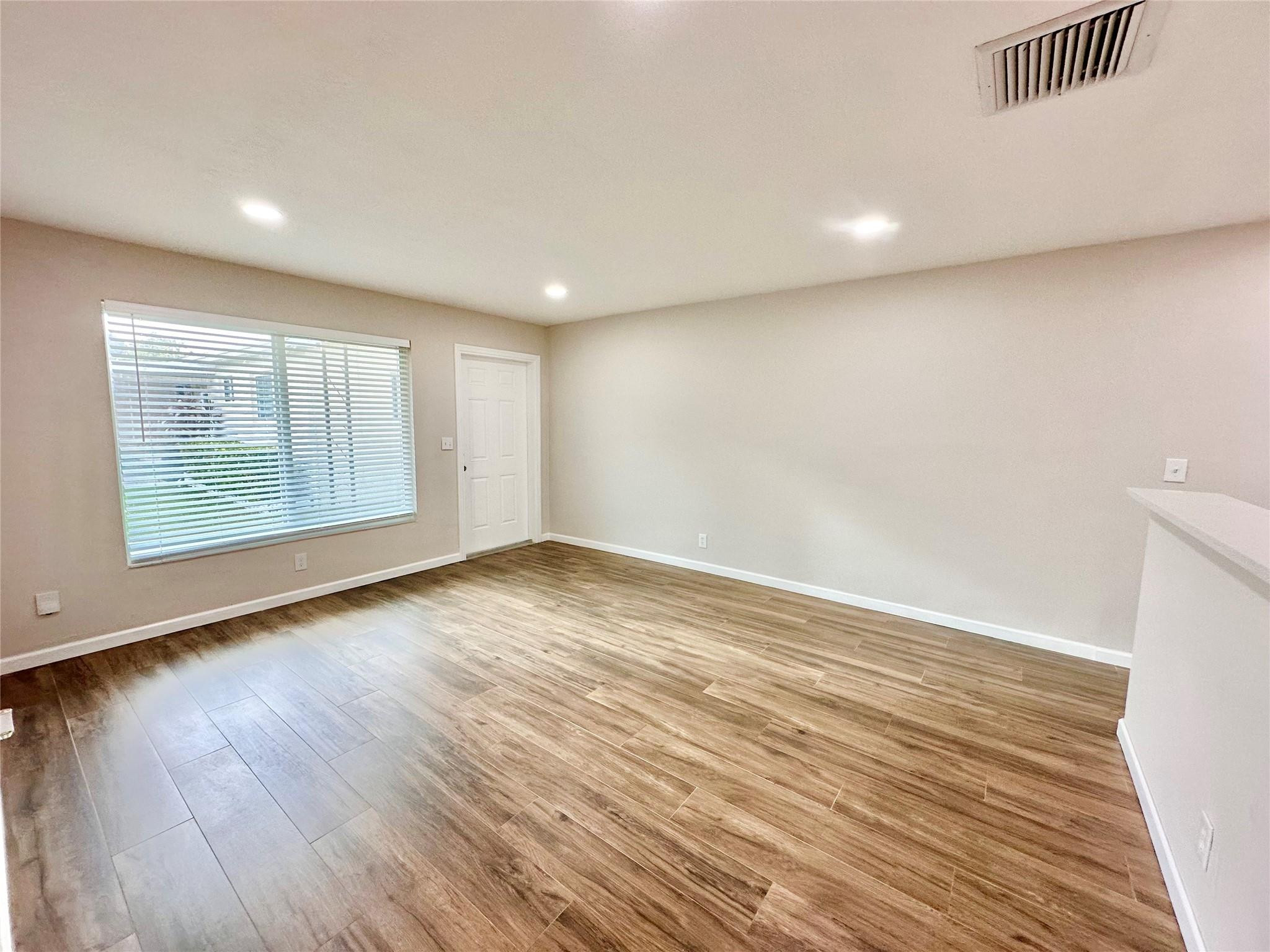 512 Southwest 11th Street, Unit A Hallandale Beach, FL 33009 - Photo 9 of 15 an empty room with wooden floor and windows