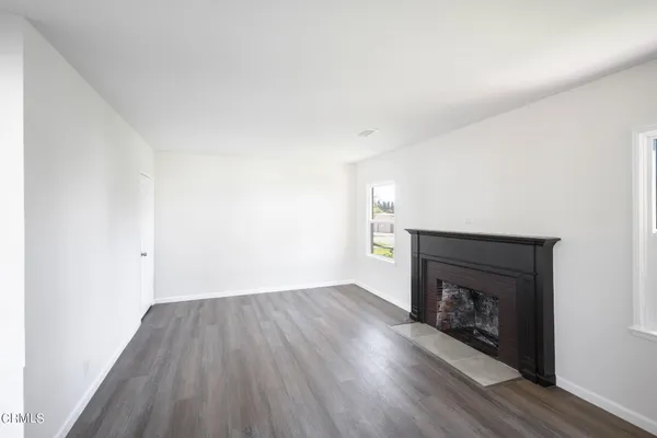 a view of an empty room with wooden floor and a fireplace