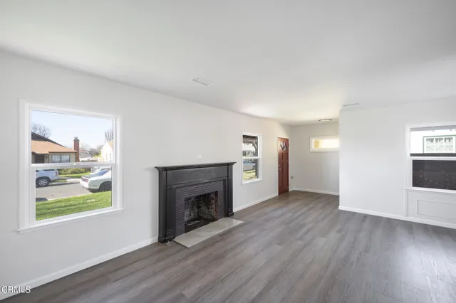 an empty room with windows a fireplace and wooden floor