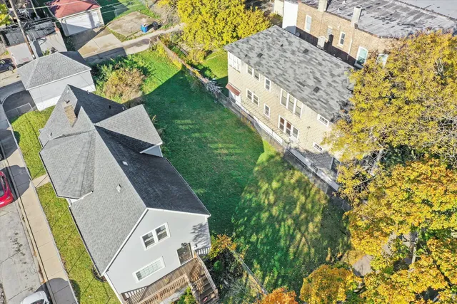 an aerial view of a house with swimming pool and large trees