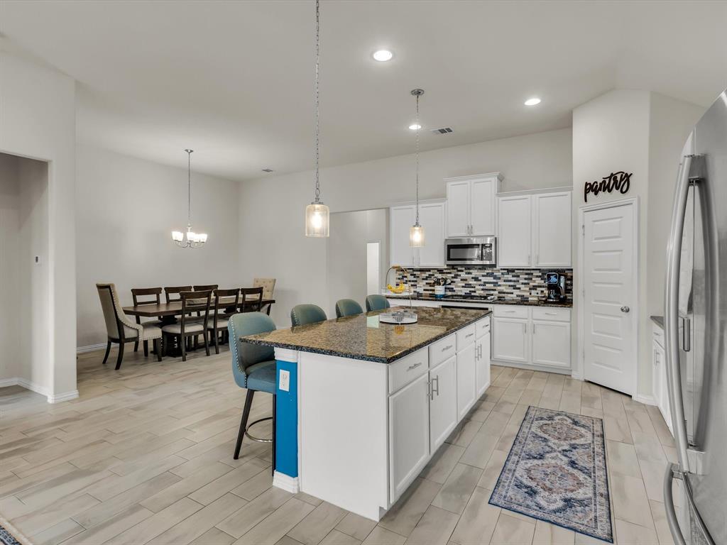 916 Monarch Lane Celina, TX 75009 - Photo 5 of 26 a kitchen with stainless steel appliances kitchen island granite countertop a stove a sink and a refrigerator