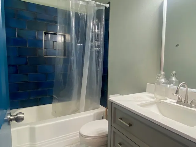 a bathroom with a granite countertop bathtub shower sink vanity and toilet