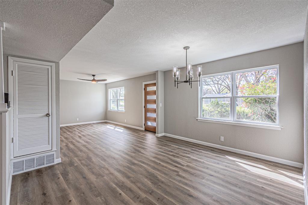 1160 Harrison Lane Hurst, TX 76053 - Photo 5 of 34 an empty room with wooden floor chandelier and windows