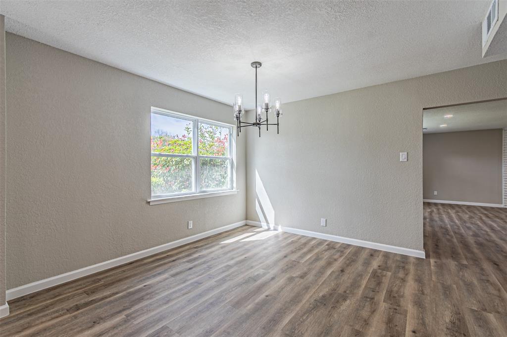 1160 Harrison Lane Hurst, TX 76053 - Photo 9 of 34 an empty room with wooden floor chandelier and windows