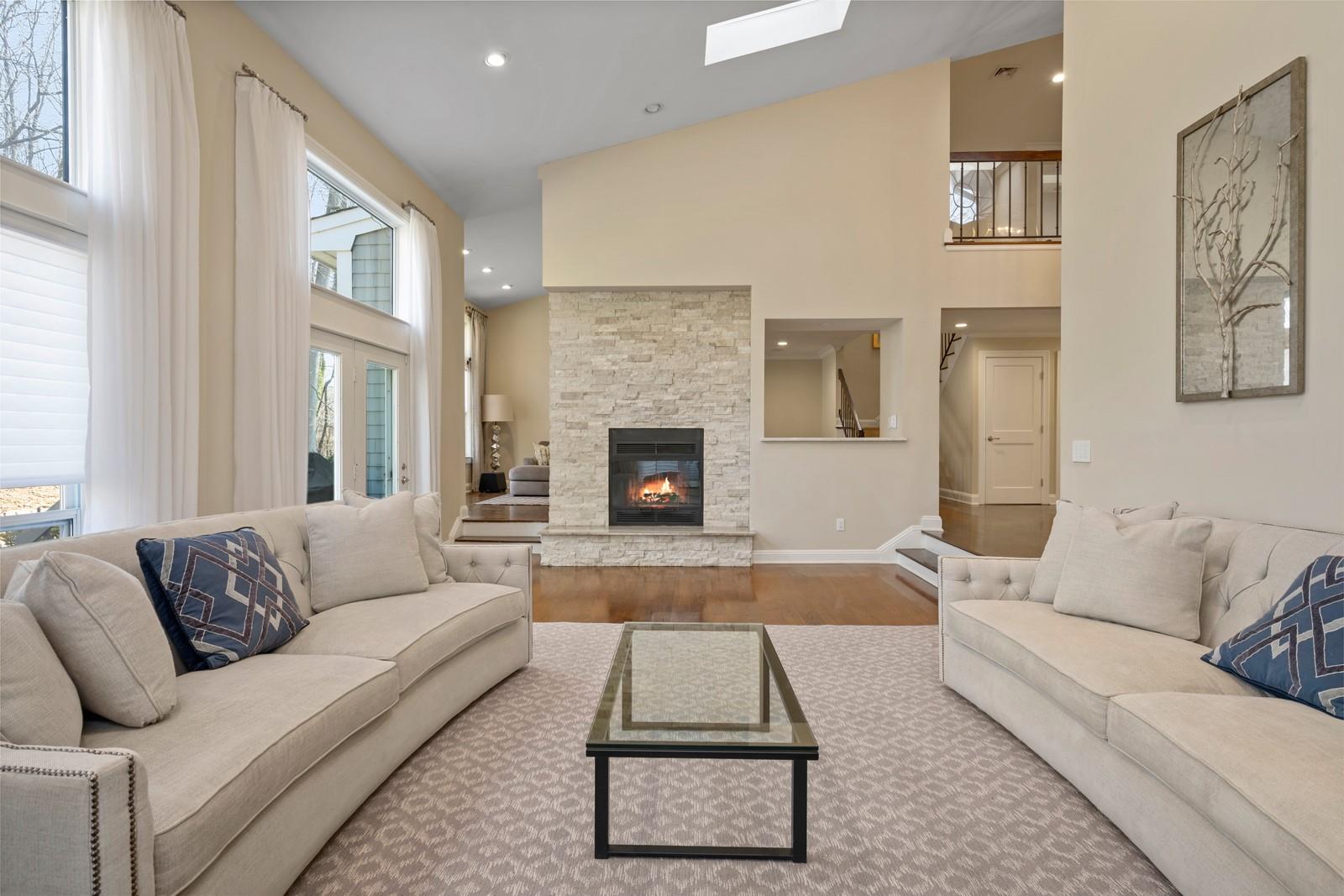 17 Tiffany Circle Manhasset, NY 11030 - Photo 1 of 1 Living room featuring a stone fireplace, stairs, high vaulted ceiling, and wood finished floors