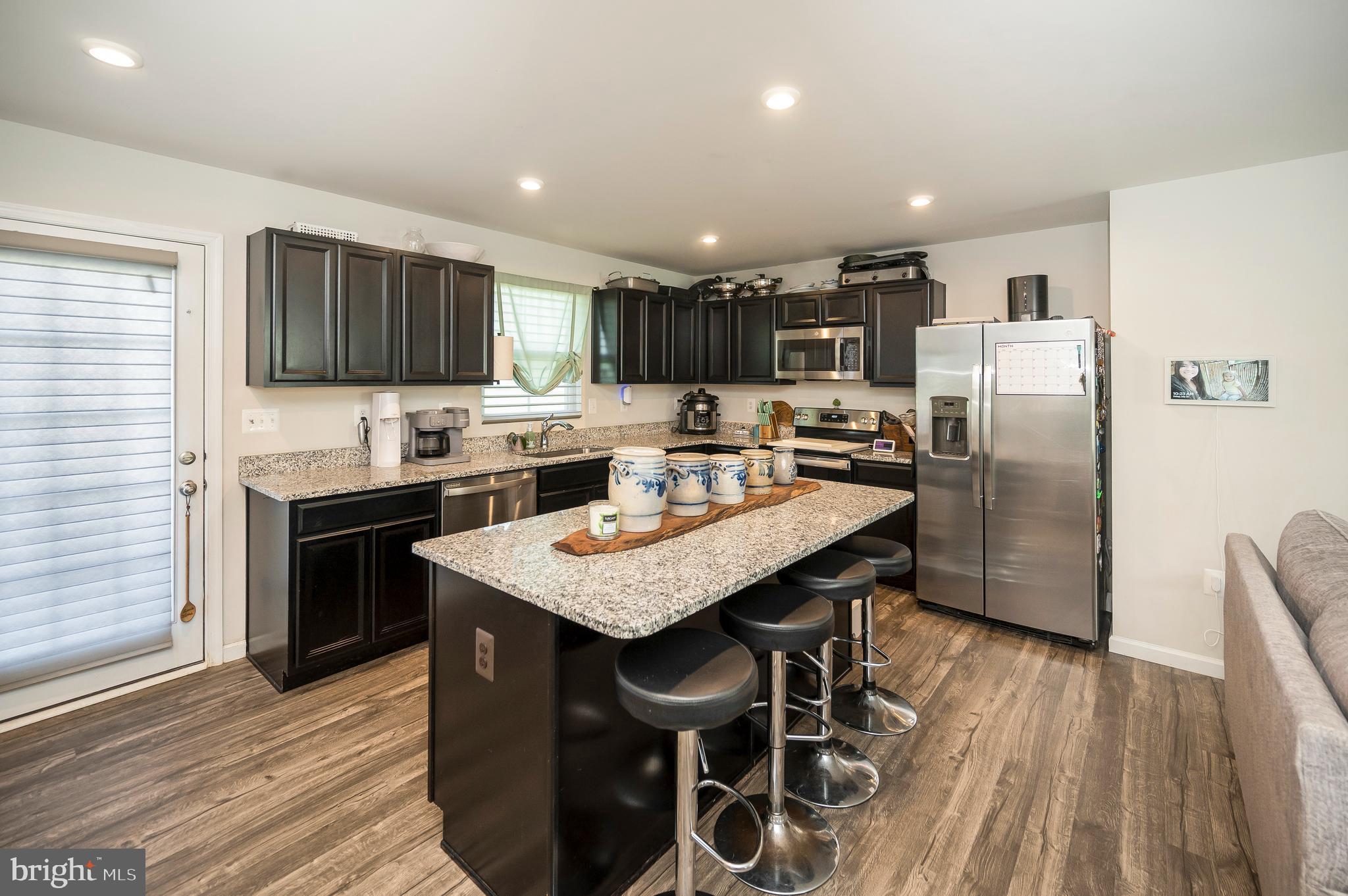 12062 Rundle Crossing King George, VA 22485 - Photo 9 of 67 a kitchen with stainless steel appliances kitchen island granite countertop a table chairs sink refrigerator and cabinets