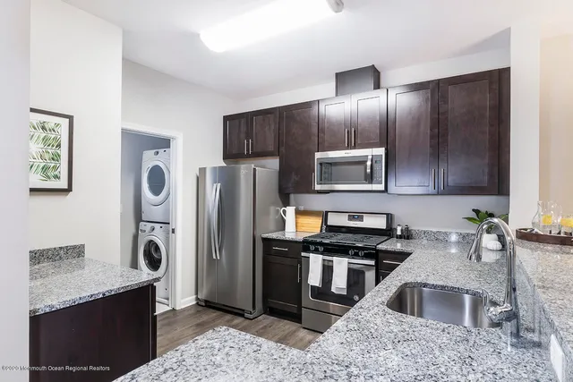 a kitchen with granite countertop stainless steel appliances a refrigerator and a sink