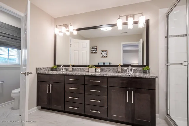 a bathroom with a granite countertop double vanity and a mirror