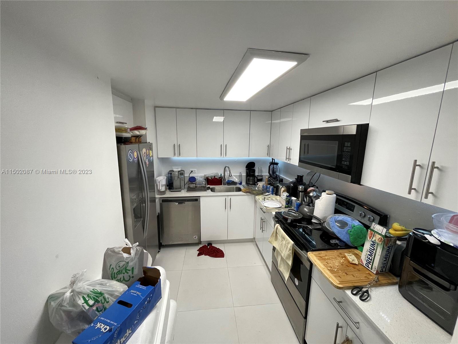 999 Brickell Bay Drive, Unit 1908 Miami, FL 33131 - Photo 38 of 57 a kitchen with refrigerator a microwave a sink and cabinets