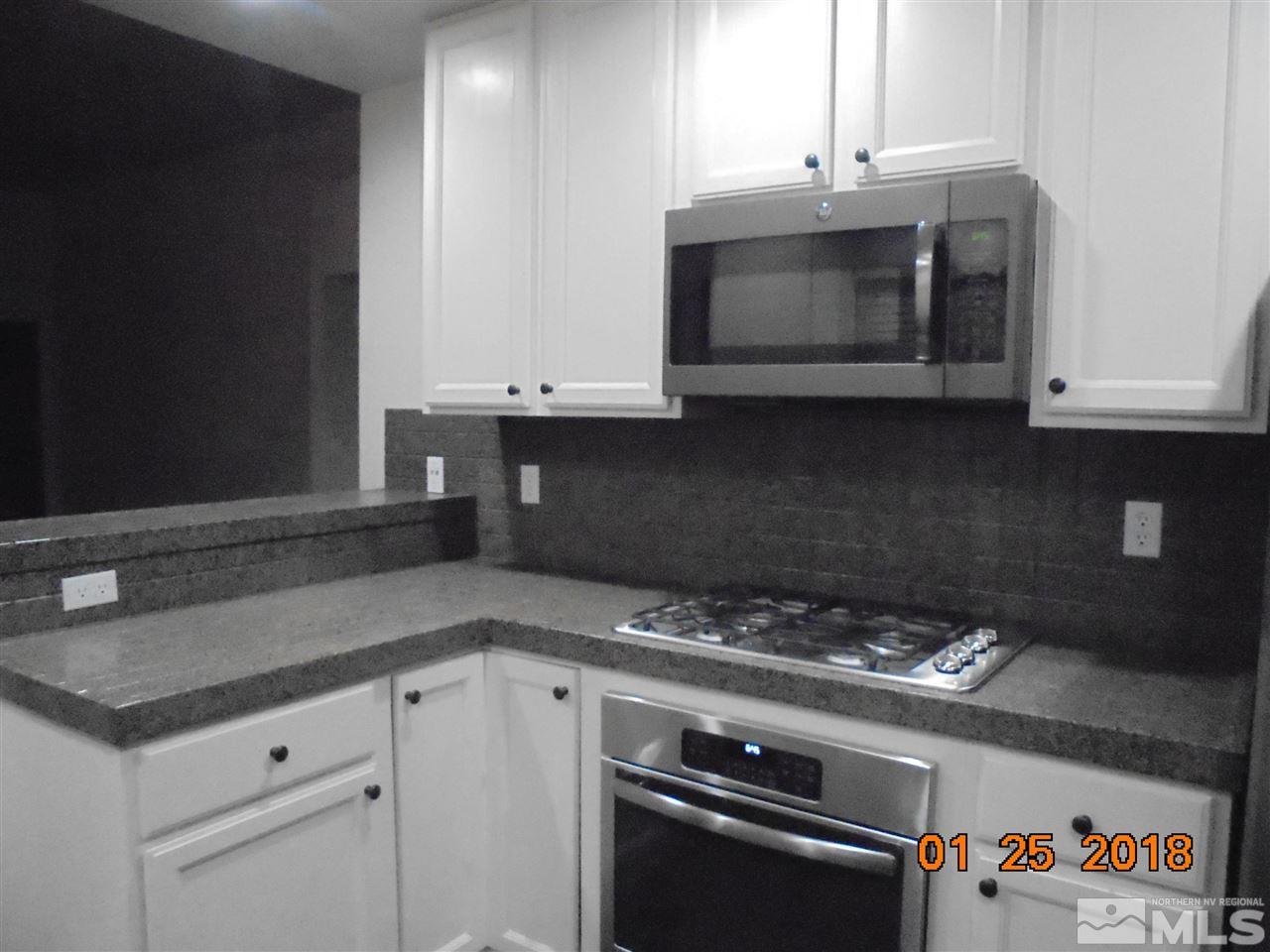 3635 Skyline Boulevard Reno, NV 89509 - Photo 14 of 37 a kitchen with granite countertop white cabinets and black appliances