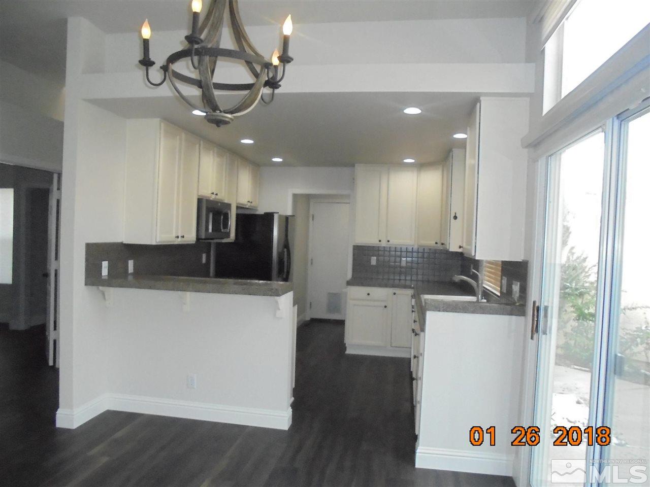 3635 Skyline Boulevard Reno, NV 89509 - Photo 26 of 37 a kitchen with stainless steel appliances granite countertop a refrigerator a stove top oven a sink dishwasher and white cabinets with wooden floor
