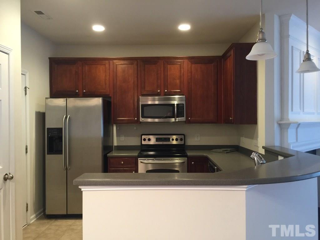 7137 Racine Way Raleigh, NC 27615 - Photo 4 of 13 a kitchen with stainless steel appliances granite countertop a sink a stove and a refrigerator with wooden floor
