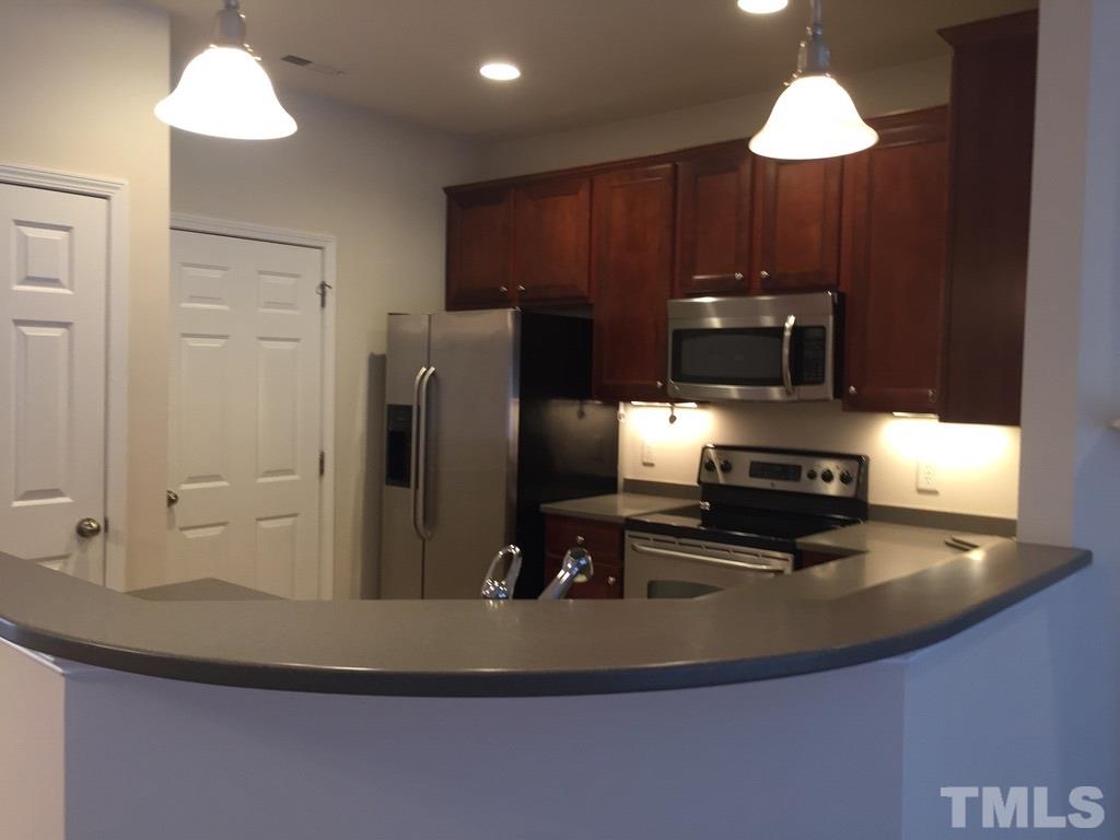 7137 Racine Way Raleigh, NC 27615 - Photo 5 of 13 a kitchen with kitchen island granite countertop a sink a refrigerator and a stove
