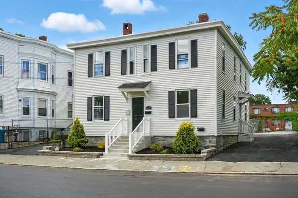 a front view of a house with a yard and parking