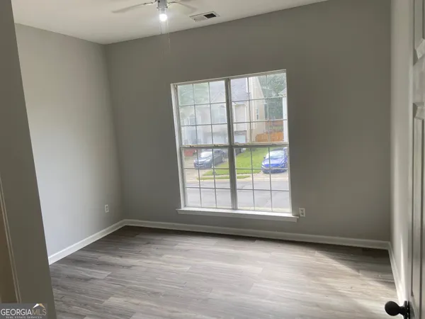 an empty room with wooden floor and windows