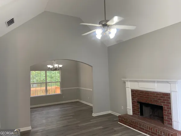 an empty room with wooden floor chandeliers a fireplace and a window