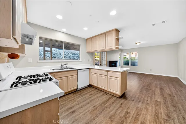 a kitchen with a white stove top oven and white cabinets with wooden floor