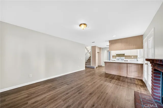 a view of a kitchen with a sink and dishwasher a stove top oven with wooden floor