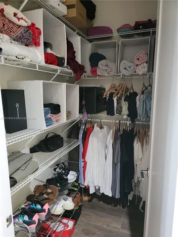 a view of walk in closet with clothes and shoes