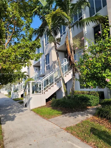 a view of a white house with a large tree