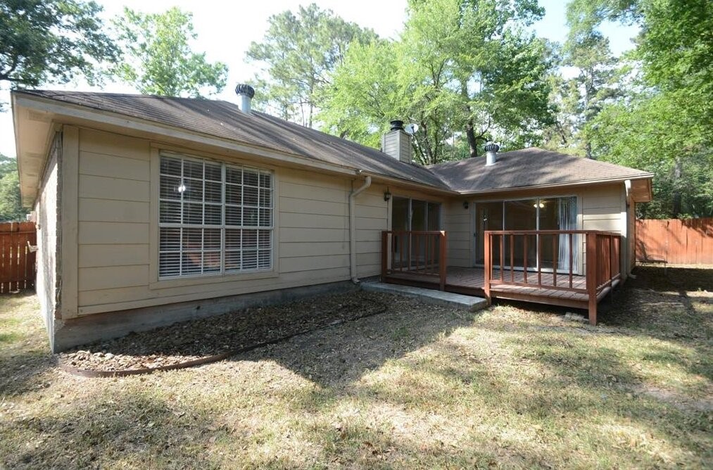 15 South Tallowberry Drive Spring, TX 77381 - Photo 23 of 26 Backyard with a wooden deck, fenced yard, and mature trees offering a private, serene outdoor space.