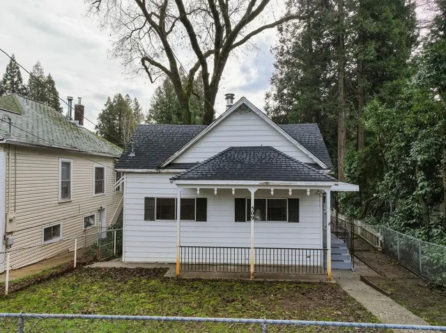 a view of a white house with a large window and wooden fence