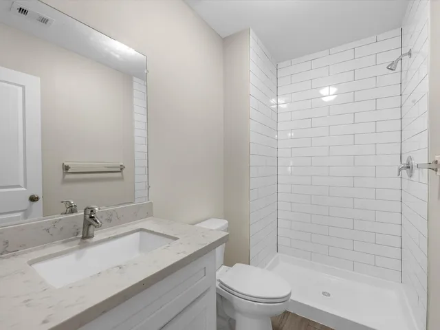 a bathroom with a granite countertop sink toilet and shower