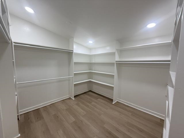 229 Coats Road Brighton, TN 38011 - Photo 8 of 14 Spacious walk-in closet featuring wood-finish flooring, recessed lighting, white built-in shelving, and multiple hanging rods