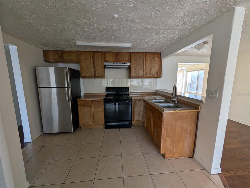 3227 Darlington Road Holiday, FL 34691 - Photo 4 of 15 a kitchen with a refrigerator a stove top oven and a sink