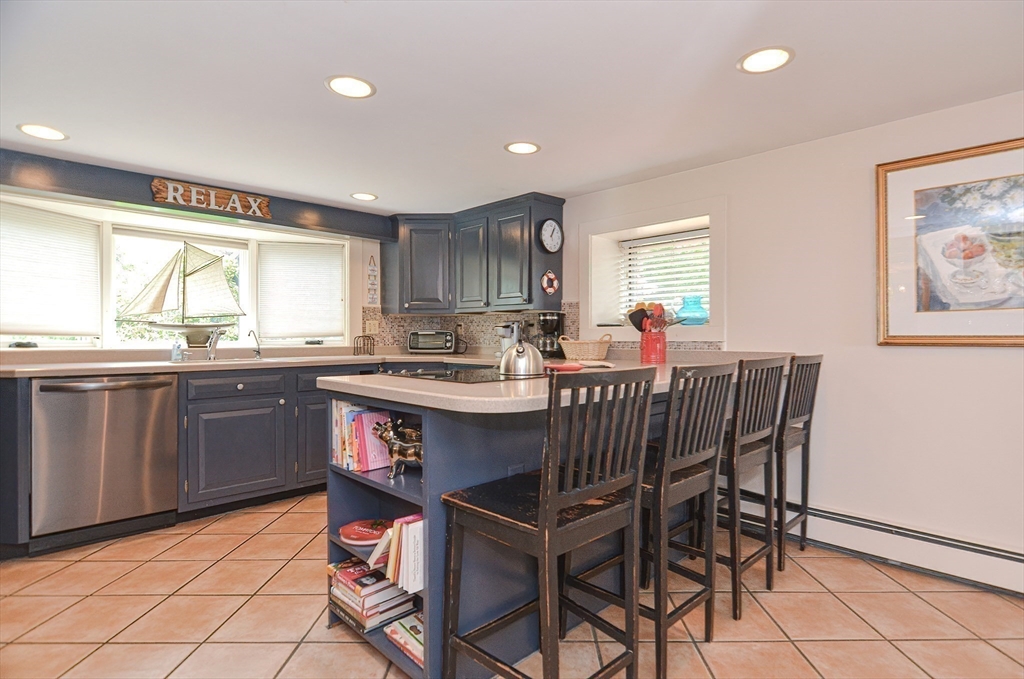 93 Granite Street, Unit 1 Rockport, MA 01966 - Photo 11 of 24 a kitchen with stainless steel appliances granite countertop a sink a stove a dining table and chairs