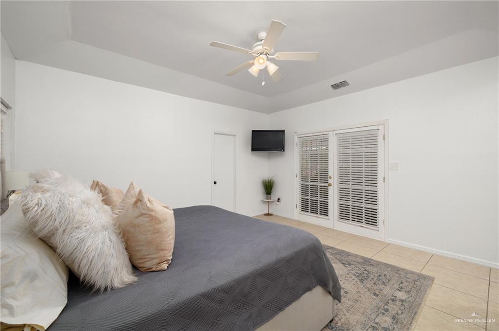 3309 South McColl Road Edinburg, TX 78539 - Photo 11 of 27 Bedroom with light tile patterned floors, a ceiling fan, and a raised ceiling