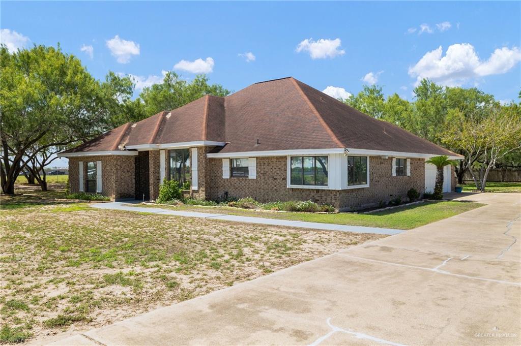3309 South McColl Road Edinburg, TX 78539 - Photo 4 of 27 View of front of property featuring a front lawn, brick siding, concrete driveway, and roof with shingles