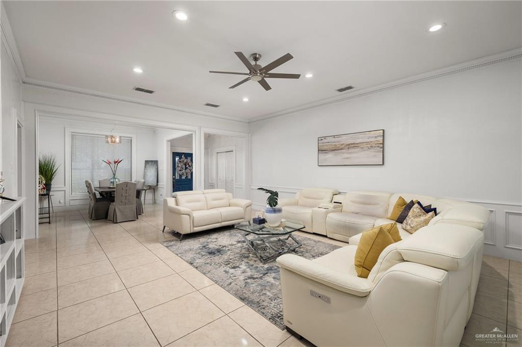 3309 South McColl Road Edinburg, TX 78539 - Photo 7 of 27 Living area with crown molding, a decorative wall, wainscoting, light tile patterned floors, and ceiling fan
