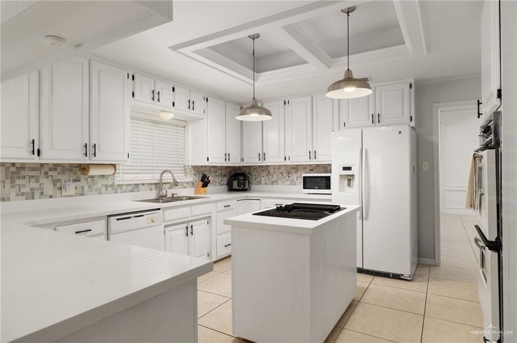 3309 South McColl Road Edinburg, TX 78539 - Photo 8 of 27 Kitchen featuring white appliances, pendant lighting, a center island, light tile patterned flooring, and coffered ceiling