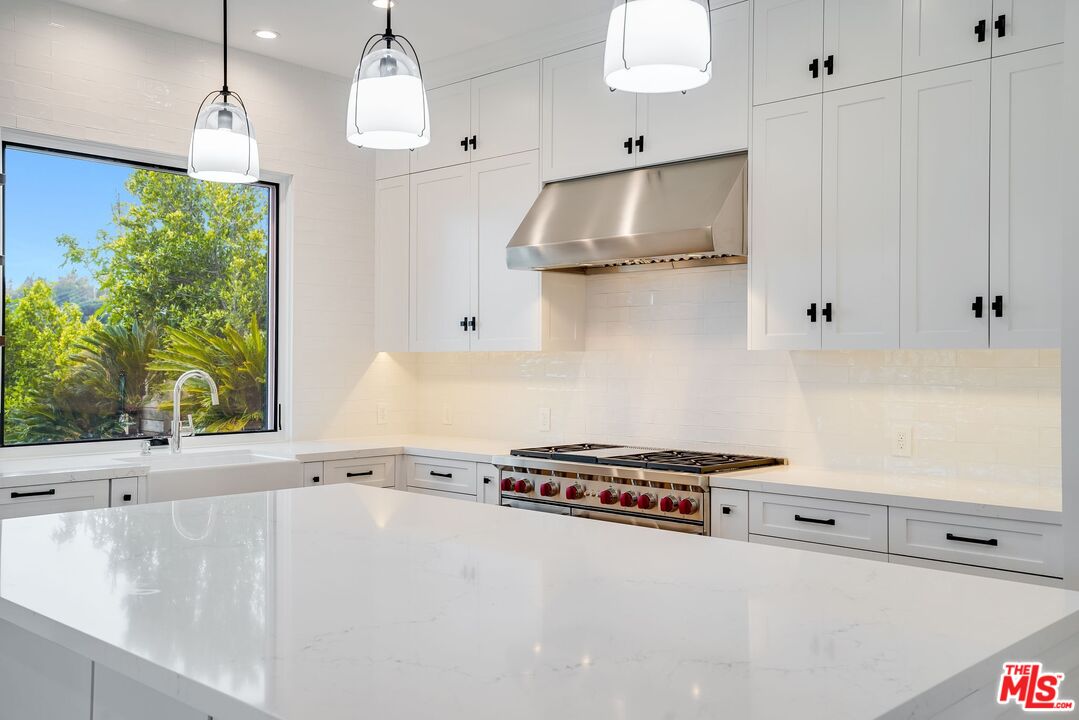 26575 Ocean View Drive Malibu, CA 90265 - Photo 9 of 39 a kitchen with stainless steel appliances a stove a sink and white cabinets