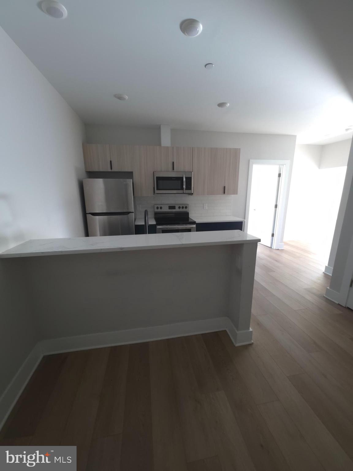 3503 Midvale Avenue, Unit 404 Philadelphia, PA 19129 - Photo 24 of 37 a kitchen with stainless steel appliances a sink a stove a microwave and wooden floor