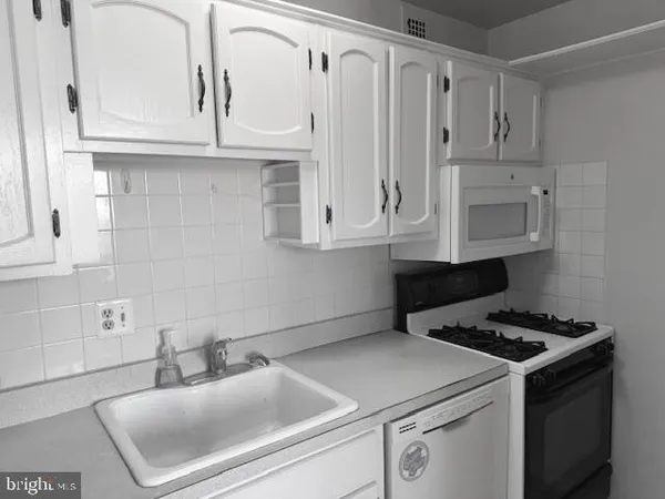 a kitchen with white cabinets and appliances